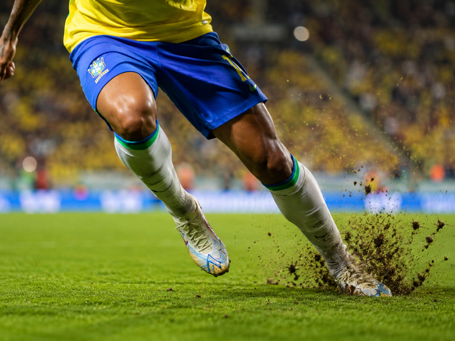 Footballer demonstrating explosive acceleration off the mark in Brazil kit.